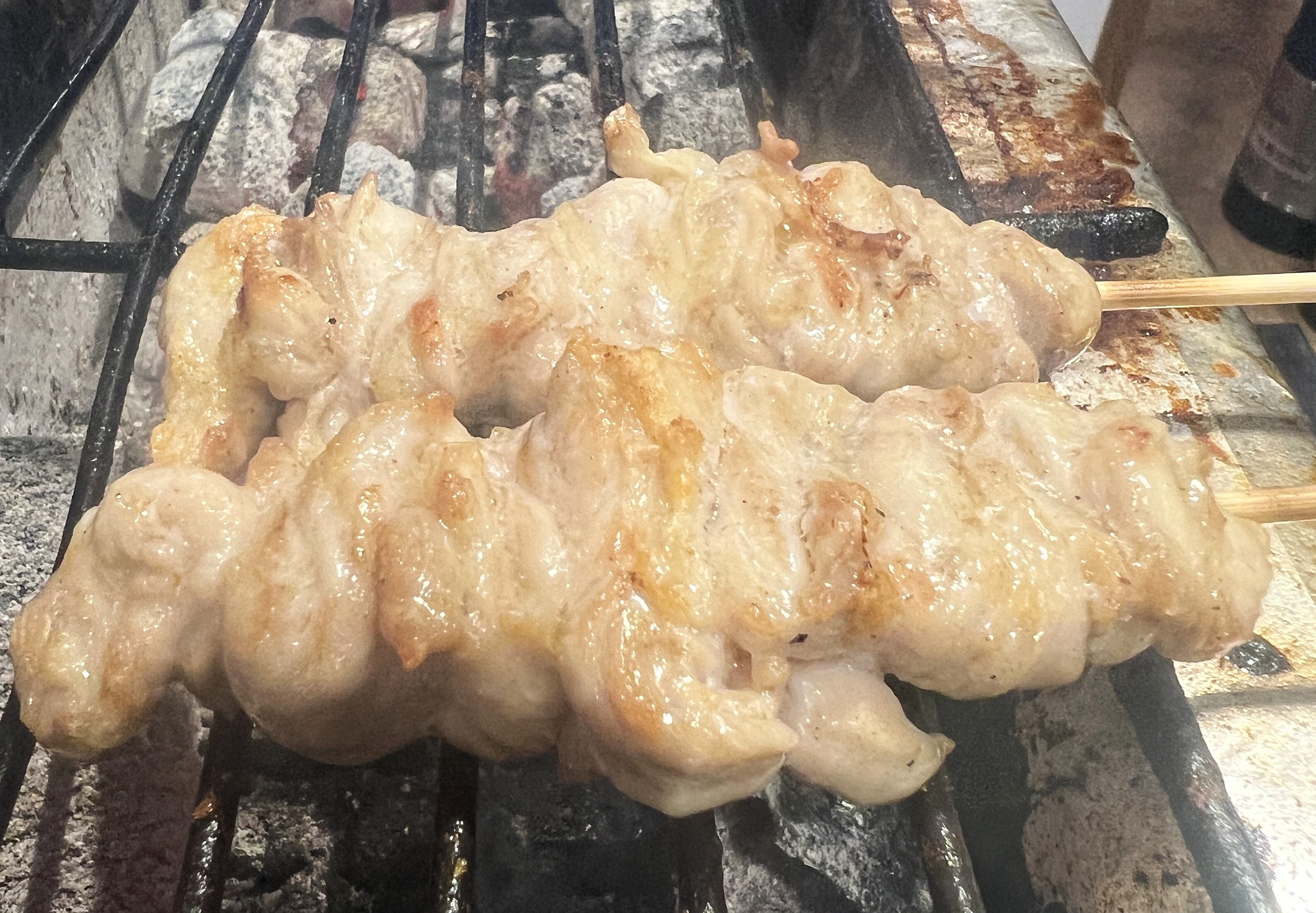炭火の焼き台で焼き上げるせせり串2本